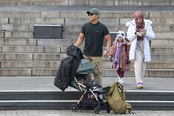 서울 남산을 찾은 관광객이 온화한 날씨 속 반팔을 입고 기념 촬영한 뒤 외투를 입기 위해 이동하고 있다. [사진=연합뉴스]