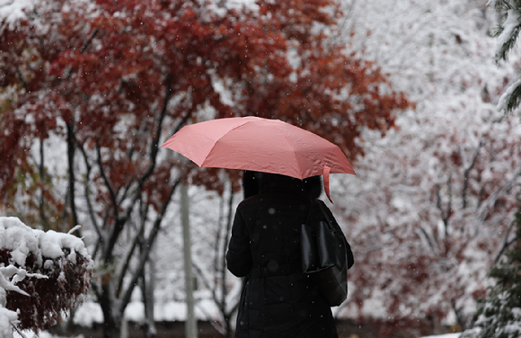 지난 27일 오전 서울 중구 덕수궁 인근에서 한 시민이 이동하고 있다. [사진=연합뉴스]