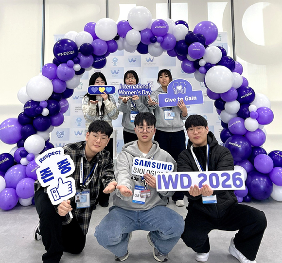 삼성바이오로직스 임직원들이 세계 여성의 날 공식 슬로건인 '나눌수록 커진다'(Give to Gain)를 의미하는 포즈를 취한 채 기념촬영을 하고 있다. [사진=삼성바이오로직스 제공]