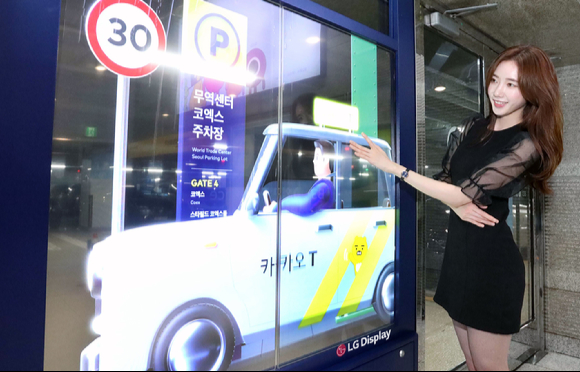 LG디스플레이 모델이 코엑스 주차장 출입문에 설치된 투명 OLED를 보고 있다. [사진=LG디스플레이]