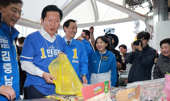 더불어민주당 정청래 총괄상임선거대책위원장이 22일 민주당 우상호 강원도지사 후보&middot;김중남 강릉시장 후보와 강원 강릉시 주문진시장을 방문해 오징어를 구입하고 있다. [사진=연합뉴스]