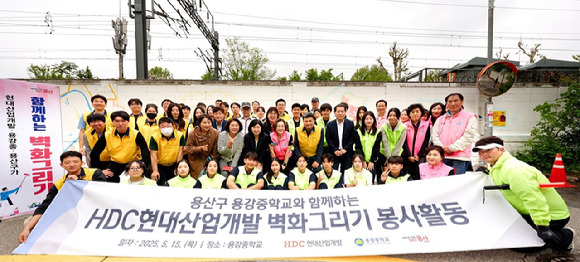 HDC현대산업개발 임직원과 박희영 용산구청장 등이 15일 서울시 용산구 용강중학교 일대 담장 벽화그리기 봉사활동 기념촬영을 하고 있다. [사진=HDC현대산업개발]