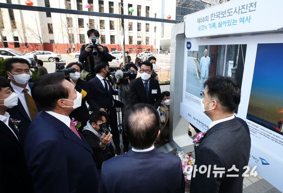 윤석열 대통령 당선인이 4일 오전 서울 중구 프레스센터광장에서 열린 제58회 한국보도사진전 개막식에 참석해 대상에 선정된 '광주 재판날 출석 않고 동네 산책하는 전두환' 사진을 보고 있다. [사진=인수위사진기자단]