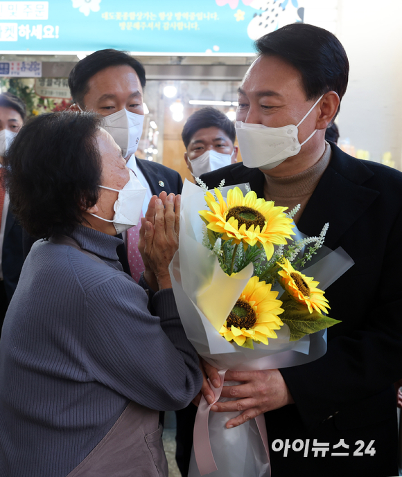 윤석열 대통령 당선인이 14일 당선 이후 첫 외부 공식일정으로 서울 남대문 시장을 찾아 한 상인으로부터 꽃다발을 받고 있다. [사진=국회사진취재단]