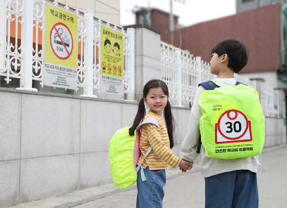 삼성전자 모델이 삼성전자와 크라운제과가 '아이 라이크 제트 봇 AI' 캠페인 일환으로 제작한 '스쿨존 가방 안전 커버' 굿즈를 선보이고 있다. [사진=삼성전자]