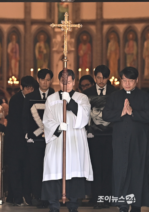 9일 서울 중구 명동성당에서 열린 故 안성기의 장례 미사가 끝난 뒤 영결식을 위해 고인의 영정과 금관문화훈장을 든 배우 정우성, 이정재가 영결식장으로 향하고 있다. [사진=곽영래 기자]