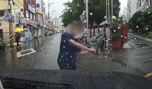 지난달 18일 오후 2시쯤 부산시 동래구에 있는 한 시장 인근 도로에서 의문의 남성이 지나가던 차량을 막고 우산을 휘두르고 있다. [사진=유튜브 '한문철TV' 캡처]