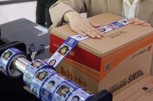 사진2-서울 강남 우체국에서 시민들이 장기 실종아동 정보가 인쇄된 ‘호프테이프’를 이용해 택배상자를 밀봉하고 있다 [사진=우본]