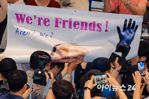 미국 조지아주 포크스턴 이민세관단속국(ICE) 구금 시설에서 체포·구금됐다 풀려난 한국인 316명이 탑승한 전세기가 12일 인천국제공항 2터미널에 도착한 가운데, 이제석 이제석광고연구소 대표가 공항 입국장에서 트럼프 미국 대통령 얼굴이 담긴 플래카드 퍼포먼스를 펼치고 있다. [사진=정소희 기자]
