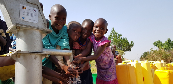이랜드리테일과 이랜드재단의 '원보틀 캠페인'을 통해 수리한 우간다 아루아지역 미테마을 식수펌프에서 아이들이 손을 씻으며 즐거워하고 있다. [사진=이랜드리테일]