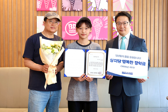 배스킨라빈스 아주대점에서 2026년 1학기 상미당 행복한 장학금 우수 장학생으로 선발된 학생(가운데)이 가맹점 대표, 행복한재단 백승훈 사무국장과 함께 기념촬영을 하고 있다. [사진=상미당홀딩스]