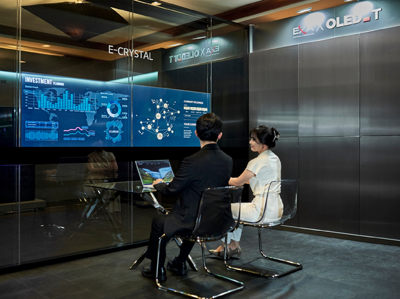 LG디스플레이 직원이 회의실 유리벽에 투명 OLED를 내장한 '회의실용 투명 OLED 솔루션(모델명 E 크리스탈)'의 활용 모습을 선보이고 있다. [사진=LG디스플레이]