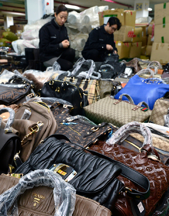 서울본부세관 압수품 창고에서 직원들이 가짜 명품 가방, 지갑, 악세사리 등 압수품을 살펴보고 있는 모습. [사진=뉴시스]