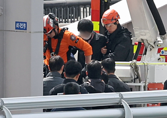 경찰관이 17일 오전 서울 한강대교 교량에서 투신 소동을 벌이던 신원 미상의 남성을 연행하고 있다. [사진=뉴시스]