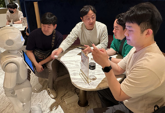 프로그램에 참여한 LGU+ 우수직원들이 일본 도쿄의 PEPPER PARLOR 카페에서 서비스 로봇 이용을 체험하고 있다. [사진=LGU+]
