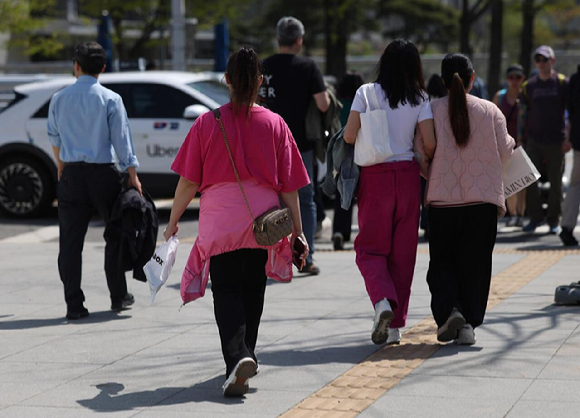 서울 광화문광장 인근에서 외국인과 시민들이 겉옷을 들거나 허리에 묶은 채 이동하고 있다. [사진=연합뉴스]