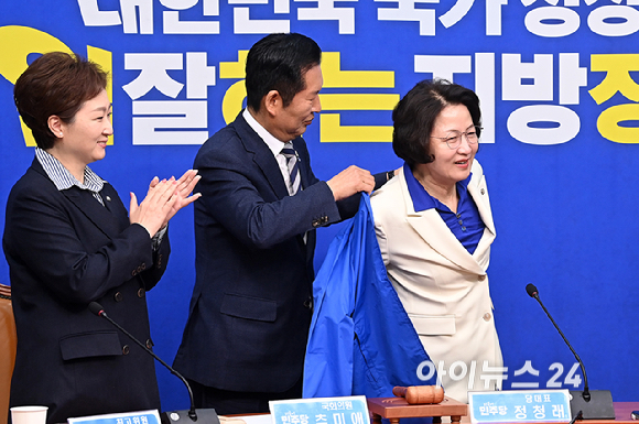 더불어민주당 정청래 대표가 13일 서울 여의도 국회에서 열린 최고위원회의에 앞서 추미애 경기도지사 후보에게 당 점퍼를 입혀주고 있다. [사진=곽영래 기자]