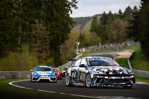 (왼쪽부터)CJ 세풀베다, 김규민, 신우진, 김영찬, 마크 바쎙, 미켈 아즈코나, 니코 바스티안이 뉘르부르크링 서킷에서 경주차 엘란트라 N1 RP(왼쪽 첫째, 둘째)와 엘란트라 N TCR을 배경으로 드라이버들이 기념촬영하고 있다. [사진=현대자동차]