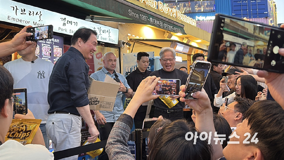 최태원 SK그룹 회장(왼쪽)과 젠슨 황 엔비디아 최고경영자(CEO)가 5일 서울 마포구 홍대 삼겹살집 '형님저요' 앞에서 SK하이닉스 HBM(고대역폭메모리) 과자칩을 들고 시민들과 소통하고 있다. [사진=정유림 기자]