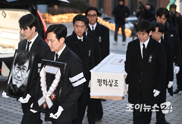 9일 서울 중구 명동성당에서 열린 故 안성기의 장례 미사가 끝난 뒤 영결식을 위해 고인의 영정과 금관문화훈장을 든 배우 정우성, 이정재가 영결식장으로 향하고 있다. [사진=곽영래 기자]