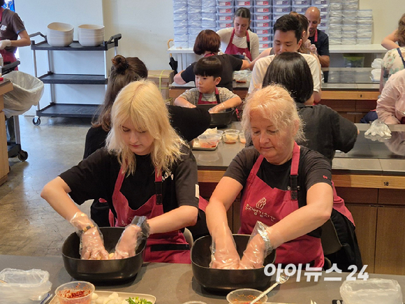 김치 만들기 체험에 참여한 외국인들이 완성된 깍두기를 밀폐용기에 담고 있다. [사진=구서윤 기자]