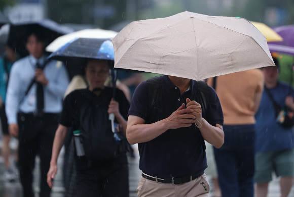 대전 서구 둔산동의 한 공원에서 시민이 우산을 쓴 채 발걸음을 재촉하고 있다. [사진=연합뉴스]