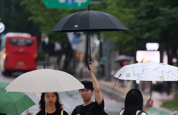 지난달 서울 종로구 광화문광장에서 한 시민이 우산을 다른 사람과 부딪히지 않게 높게 들고 횡단보도를 건너고 있다. [사진=뉴시스]