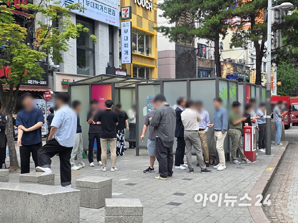 지난 25일 서울 명동의 한 흡연부스 앞. 다수의 흡연자들이 부스 밖 금연구역에서 담배를 피우고 있다. [사진=구서윤 기자]
