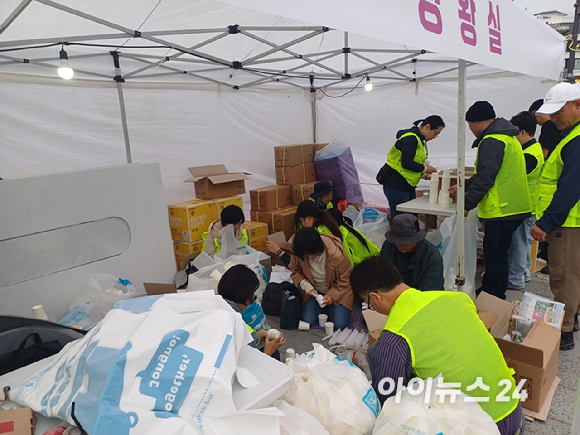 16일 오후 서울 광화문 북측광장 인근에서 더불어민주당 주최로 열린 '김건희 윤석열 국정농단 규탄·특검 촉구 제3차 국민 행동의 날' 장외 집회에 앞서 관계자들이 양초를 종이컵에 끼우고 있다. [사진=라창현 기자]