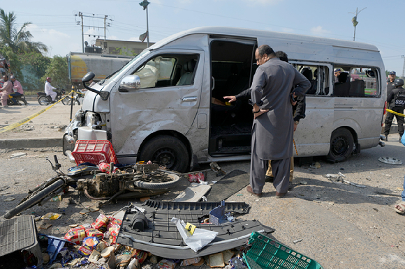 19일(현지시각) 파키스탄 카라치에서 자폭 테러가 발생해 경찰관들이 피해 승합차를 조사하고 있다. 2024.04.19. [사진=AP/뉴시스]