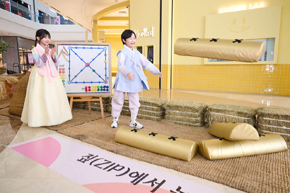 스타필드 하남에서 진행 중인 '짚(ZIP)에서 놀자' 팝업 전시에서 어린이 모델들이 윷놀이를 하고 있다. [사진=신세계프라퍼티]