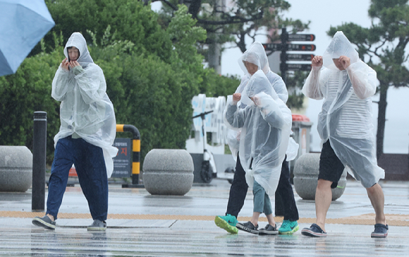 장마가 시작된 1일 부산 해운대구 구남로에서 비옷을 입은 관광객들이 발걸음을 옮기고 있다. [사진=연합뉴스]
