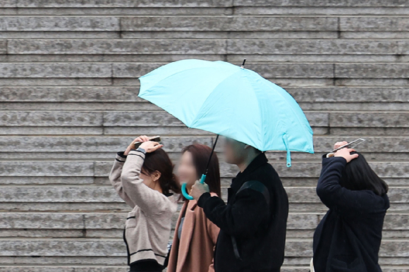 지난 18일 오후 서울 종로구 광화문광장에서 우산을 준비 못한 시민들이 머리를 손으로 가리고 이동하고 있다. [사진=뉴시스]