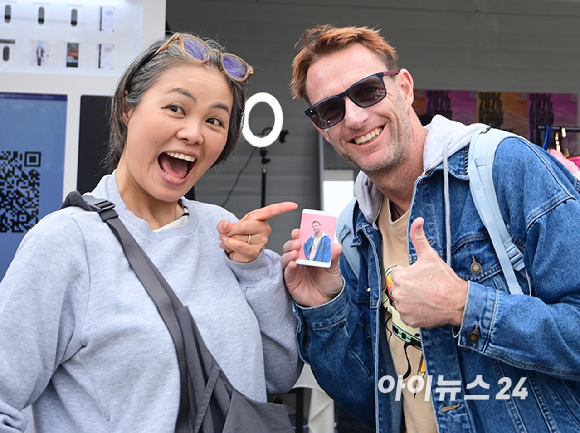 10일 서울 여의도 한강공원에서 열린 '2026 서울 스프링 페스티벌' 케이팝아케이드 부스에서 외국인 관광객이 포토카드 만들기 체험을 하고 즐거워하고 있다. [사진=정소희 기자]