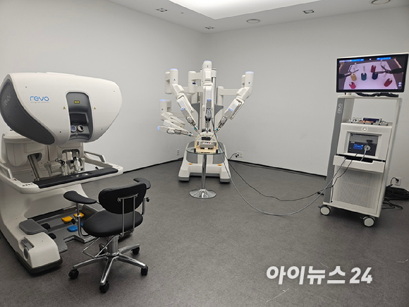 기자가 마스터콘솔에 앉아 암컨트롤러에 연결된 벨트에 엄지와 중지를 넣고 조작을 하고 있는 모습이다. [사진=설재윤 기자]