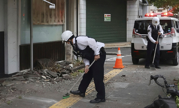 일본 서부 에히메현 우와지마에서 경관들이 지진으로 발생한 파편들을 치우고 있다. 2024.04.18. [사진=뉴시스/AP]