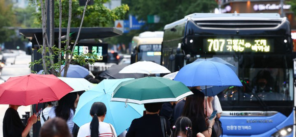 지난 14일 서울 시내에 소나기가 내리는 가운데 종로구 세종대로에서 시민들이 비를 피해 퇴근하고 있다. [사진=뉴시스]