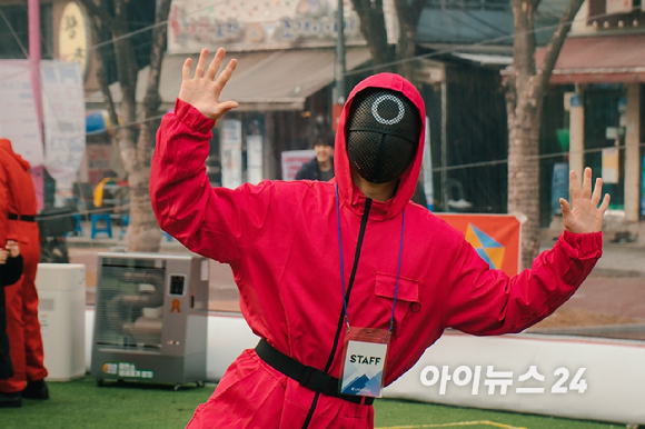 지난 1월 29일 오후 서울 마포구 홍대 레드로드 R1존 에어돔에서 '홍대 에어돔 K-유니버스 페스티벌'이 진행된 가운데 오징어게임 마스크 솔져로 변신한 진행요원이 익살스런 포즈를 취하고 있다. [사진=케이유니버스]