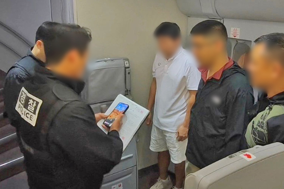 경찰청은 1일 '마약왕'으로 불리는 박왕열에게 필로폰 등 마약류를 공급한 혐의를 받는 최모씨(오른쪽 세 번째)를 태국에서 강제 송환했다고 밝혔다. 사진은 경찰이 최씨에게 기내에서 체포영장을 집행하는 모습. [사진=연합뉴스]