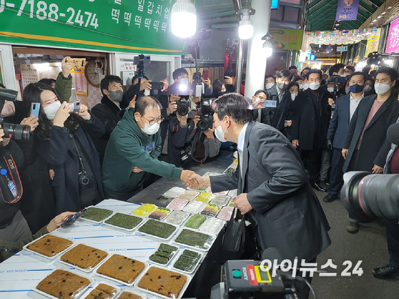 윤석열 국민의힘 대선후보가 10일 강원도 강릉중앙시장의 한 떡 가게에서 상인과 악수하고 있다. [사진=정호영 기자]