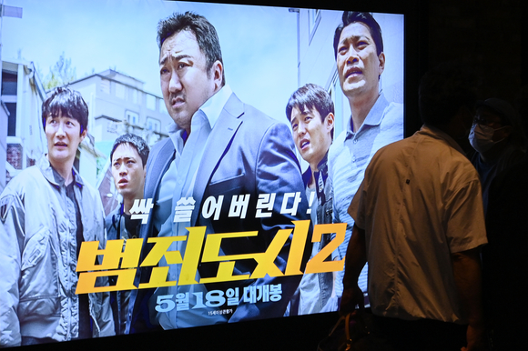 7일 오후 서울 CGV 용산아이파크몰에서 영화 '범죄도시2' 포스터 앞으로 시민들이 지나가고 있다. [사진=김성진 기자]