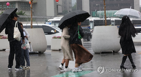 서울 광화문광장 부근에서 우산을 든 외국인 관광객들이 비바람을 맞으며이동하고 있다. [사진=연합뉴스]