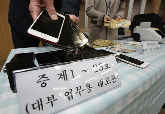 서울 동대문경찰서 관계자들이 지난 2023년 10월 30일 동대문경찰서에서 열린 '나체추심' 불법대부업체 조직 11명 검거 브리핑에서 증거물품을 공개하고 있다. [사진=뉴시스]