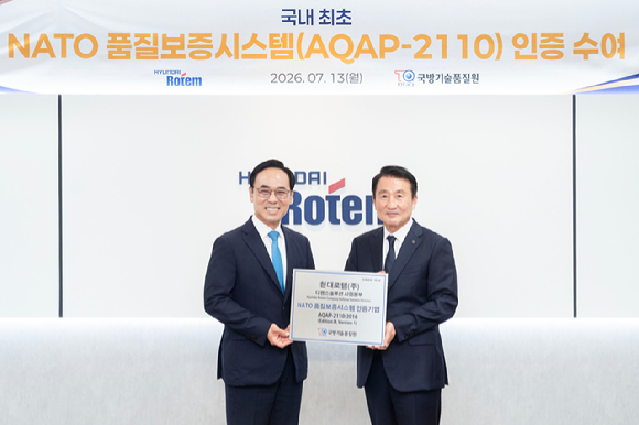 신상범 기품원장(오른쪽)과 이용배 현대로템 사장이 지난 13일 현대로템 의왕 본사에서 나토 품질보증시스템 인증 수여식을 마친 후 기념촬영을 하고 있다. [사진=현대로템]