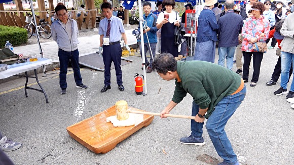 행사에 참여한 한 시민이 포항불교사암연합회신도회가 마련한 떡메치기를 하고 있다.  [사진=경북언론인불자회]