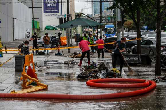 연일 기록적인 폭우가 소강 상태를 보인 10일 오전 서울 서초구 서초대로 인근 빌딩에서 관계자들이 인도를 청소하고 있다. [사진=뉴시스]