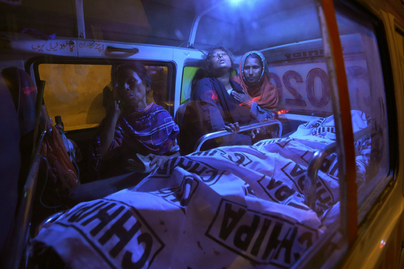 지난달 31일(현지시간) 파키스탄 카라치의 한 공장 밖 라마단 음식 무료 배급소에서 발생한 압사 사고로 숨진 희생자들의 가족이 구급차 안 시신 앞에서 흐느끼고 있다. 이 사고로 어린이 3명과 여성 8명 등 지금까지 최소 11명이 숨진 것으로 나타났다. [사진=뉴시스]