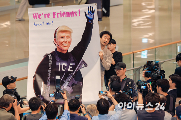 미국 조지아주 포크스턴 이민세관단속국(ICE) 구금 시설에서 체포·구금됐다 풀려난 한국인 316명이 탑승한 전세기가 12일 인천국제공항 2터미널에 도착한 가운데, 이제석 이제석광고연구소 대표가 공항 입국장에서 트럼프 미국 대통령 얼굴이 담긴 플래카드 퍼포먼스를 펼치고 있다. [사진=정소희 기자]
