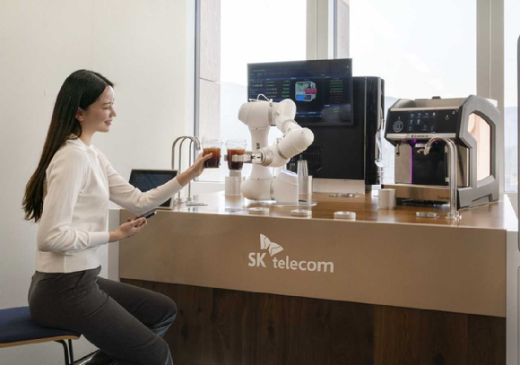 모델이 무인 커피로봇 서비스 'AI바리스타로봇'을 소개하고 있는 모습. [사진=SKT]