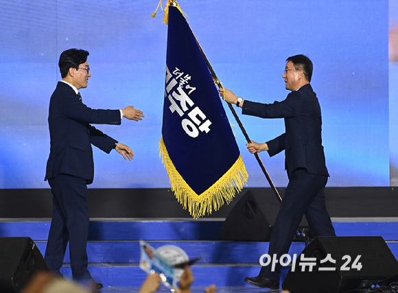 김민석 더불어민주당 신임 당 대표가 17일 대전 컨벤션센터에서 열린 제3회 더불어민주당 정기 전국당원대회에서 당 대표로 선출된 뒤 한병도 원내대표에게 당기를 건네받고 있다. [사진=곽영래 기자]